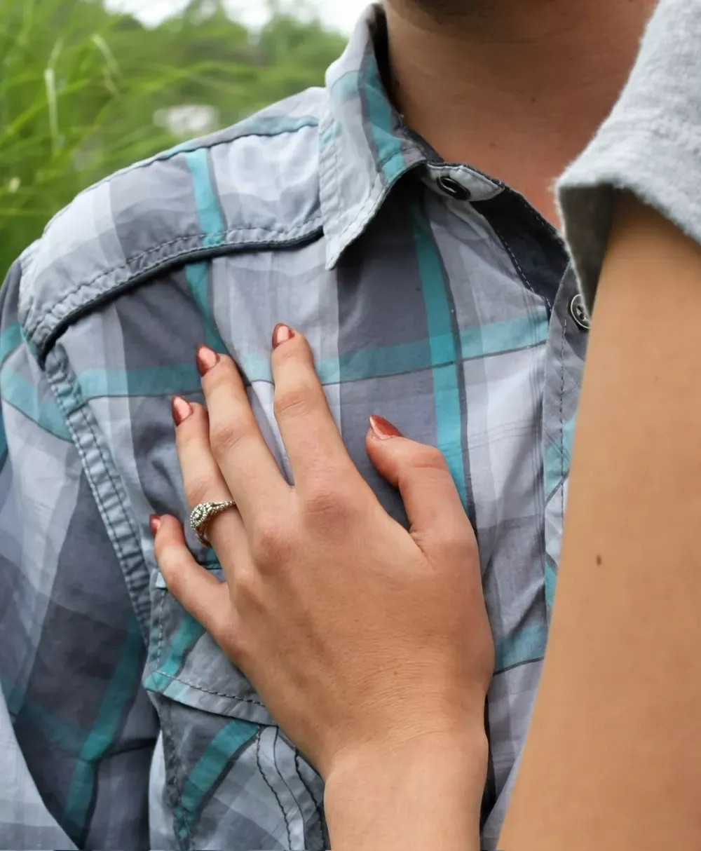 Close-up of an engagement ring resting against a partner's shirt